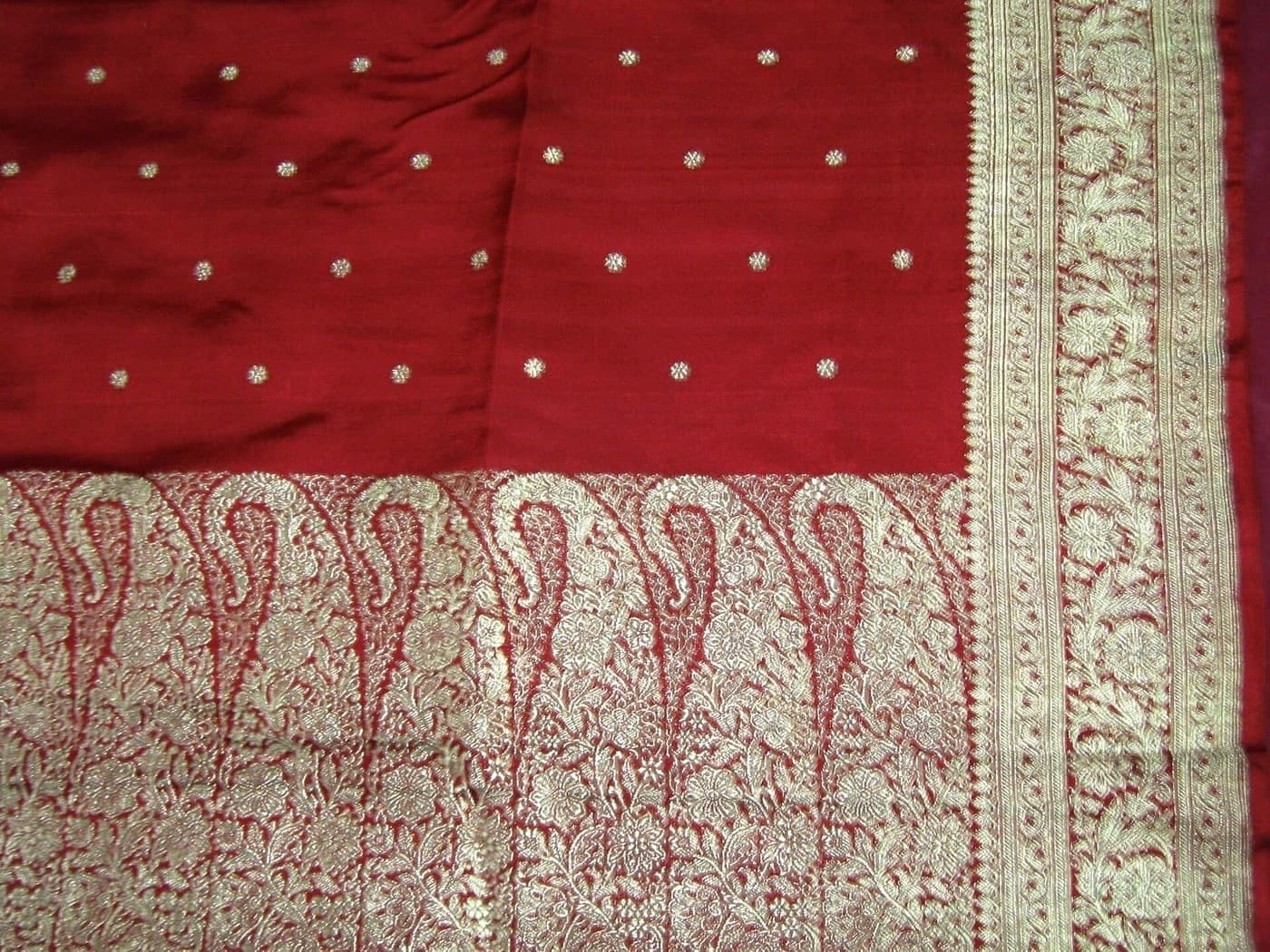 Deep red silk saree with scattered gold butis above a broad gold paisley pallu